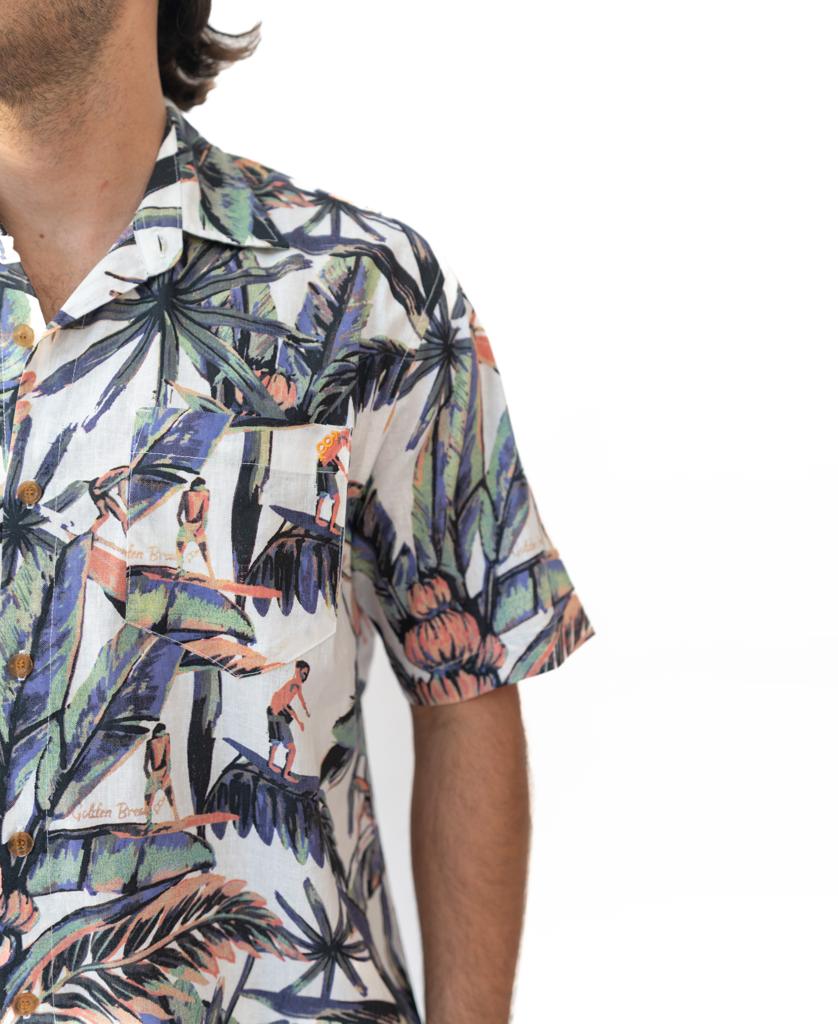 A person wears the Golden Breed Surfer Palm Shirt in Off White—a short-sleeve, button-up with a colorful leaf and surfer print—shown from neck to mid-torso against a white background.