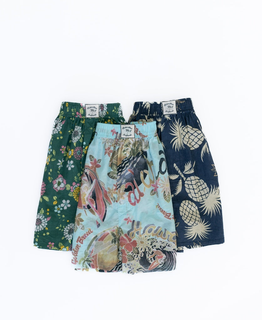 Three pairs of Golden Breed Tyson Boxer Shorts in floral, tropical print, and pineapples patterns are displayed side by side on a white background. Made from 100% cotton, these Vintage Navy shorts combine comfort with classic style.