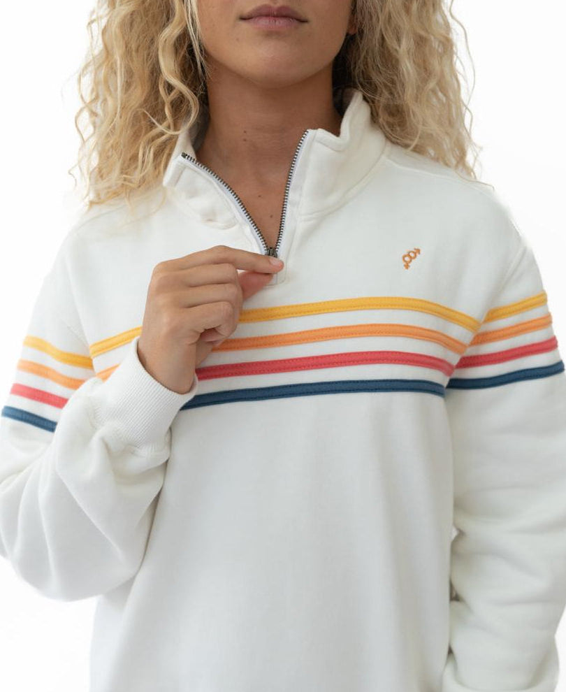 A woman wears the Golden Breed Long Island 1/4 Zip in Off White, featuring orange, pink, and blue horizontal stripes, holding the zipper near her collar.