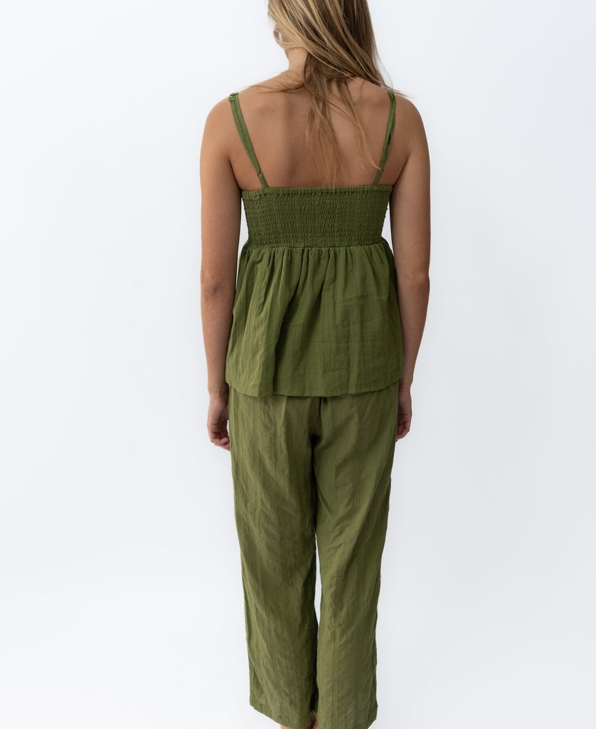 A woman faces away wearing the Lazy Beach Celine | Khaki Stripe set—an olive green cotton spaghetti strap top and matching wide-leg pants—set against a plain white background.