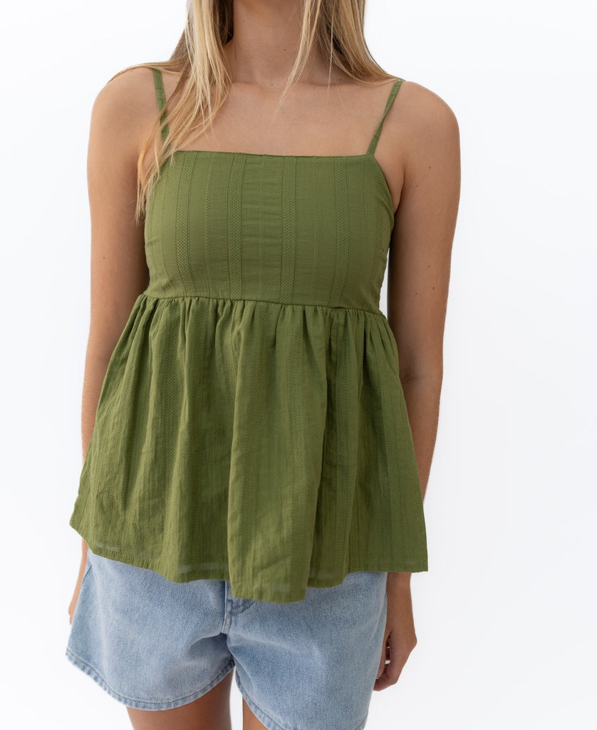 A person is wearing the Lazy Beach Celine | Khaki Stripe sleeveless, square-neck top with thin straps and light blue denim shorts, standing against a plain white background.