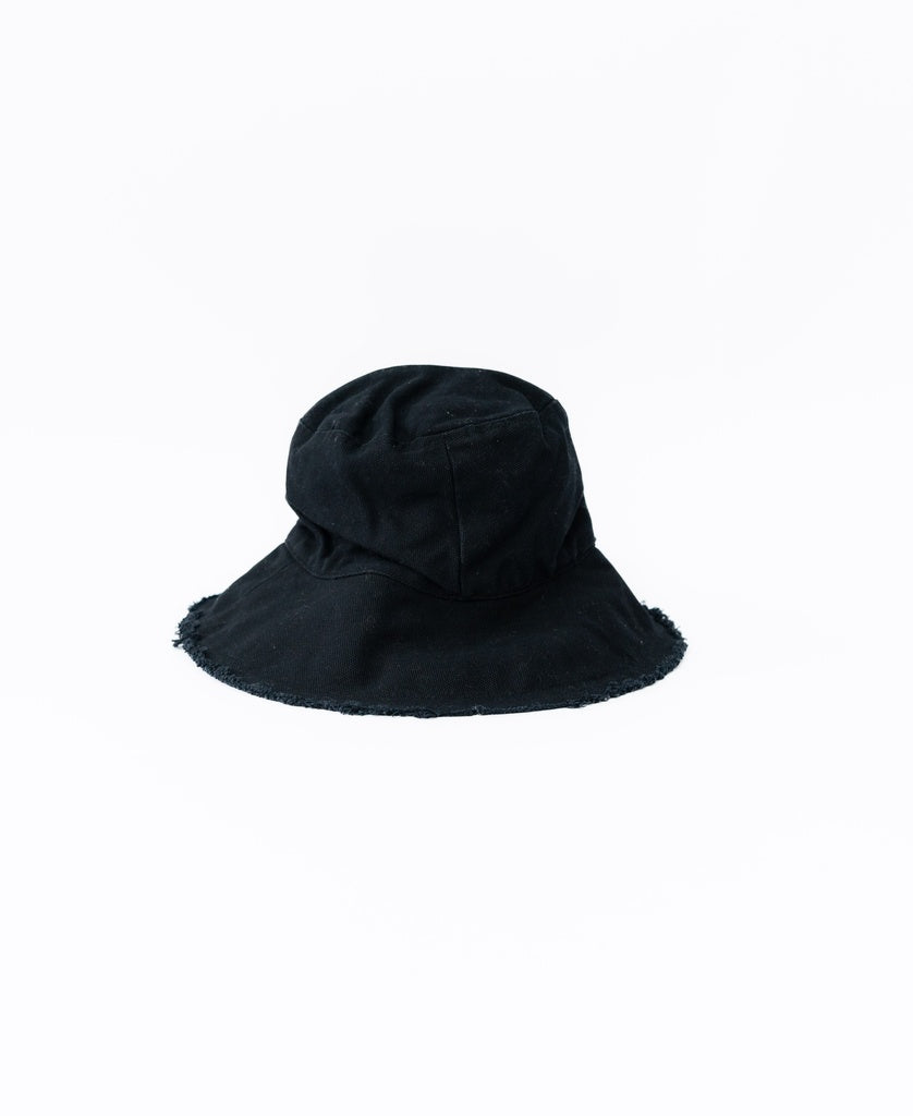 The Lazy Beach Halo Bucket Hat in black, featuring frayed edges and crafted from handmade cotton, is shown against a white background.