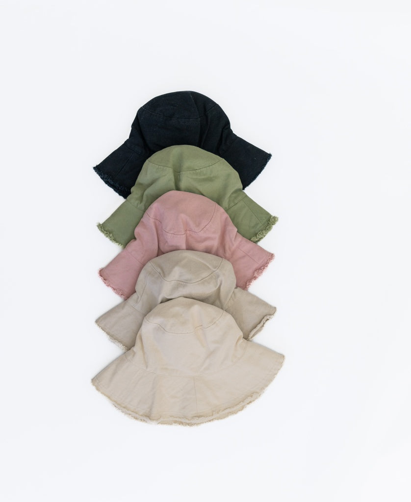 The Lazy Beach Halo Bucket Hat in Blush is displayed vertically with other colors on a white background. Each cotton hat is handmade in Indonesia for premium comfort and style.