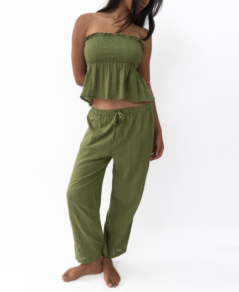 A person wearing Lazy Beachs Liberty Pant in Khaki, featuring a loose fit and elastic waist in soft cotton, stands barefoot against a plain white background.