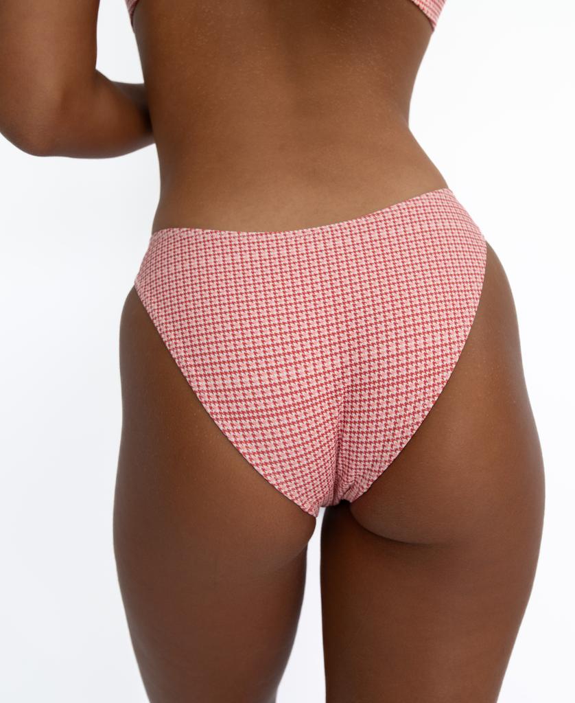 A person is shown from the back against a white background, wearing Lazy Beach’s Millie Bottom in pink houndstooth, crafted from sustainable Italian fabric.