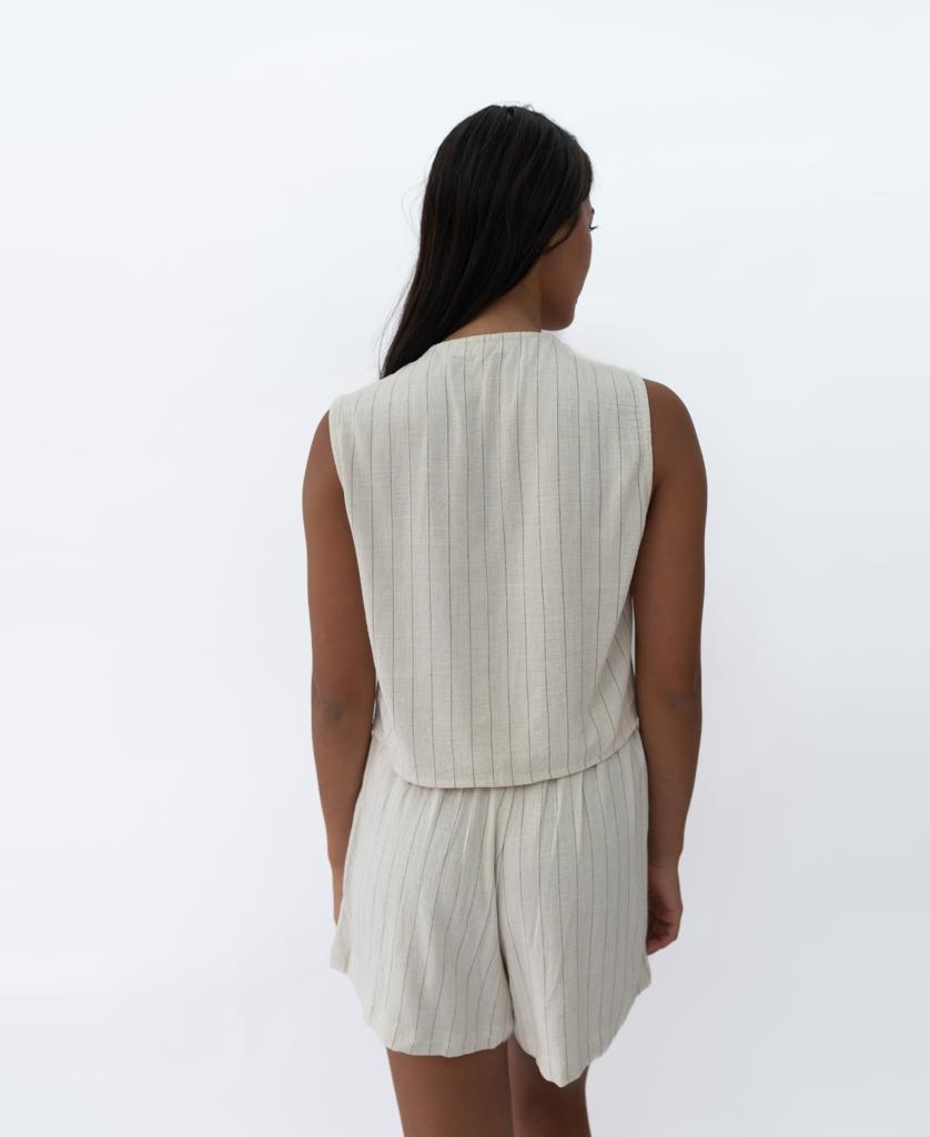 A person with long dark hair, seen from behind, is wearing the Lazy Beach Rennie Vest in Off White Fine Pinstripe and matching shorts, set against a plain white background.