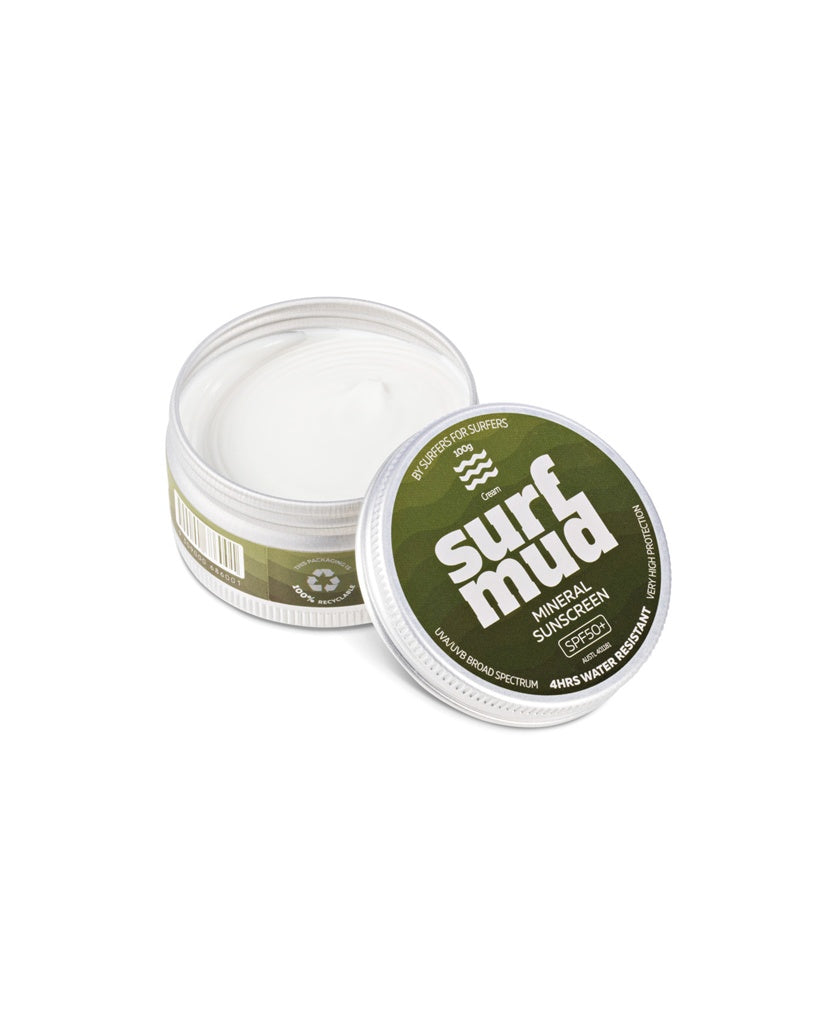 A Surf Mud Mineral Sunscreen Tin SPF50+ sits open with the lid off to the side, showing the white cream inside.