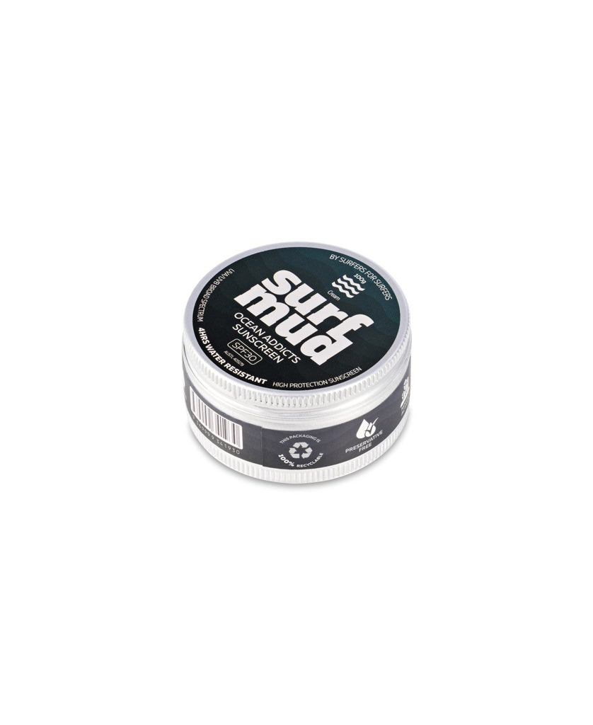 A round tin of Ocean Addicts Sunscreen SPF30 by Surf Mud, with a black and white label, is seen from a slight angle—ideal for ocean sports lovers seeking water-resistant, non-nano zinc oxide protection.