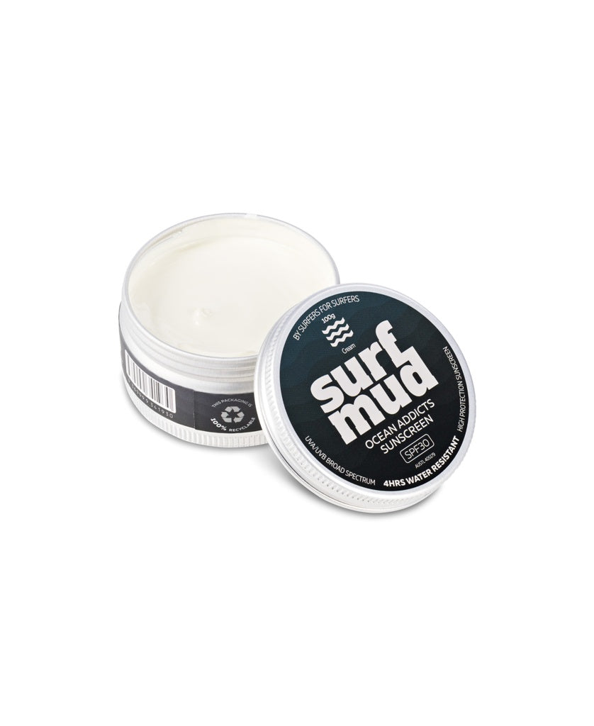 A round Surf Mud Ocean Addicts Sunscreen Tin SPF30 sits open, revealing the cream. The lid highlights SPF 30, water resistance, and non-nano zinc oxide—safe, ocean-friendly sun protection ideal for water sports.