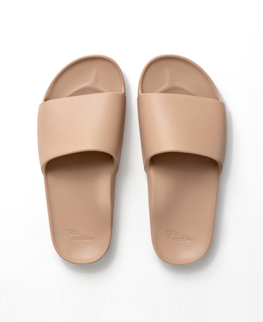 A pair of Archie Slide | Tan by Archies, made from closed cell foam with textured footbeds, shown from above on a white background.