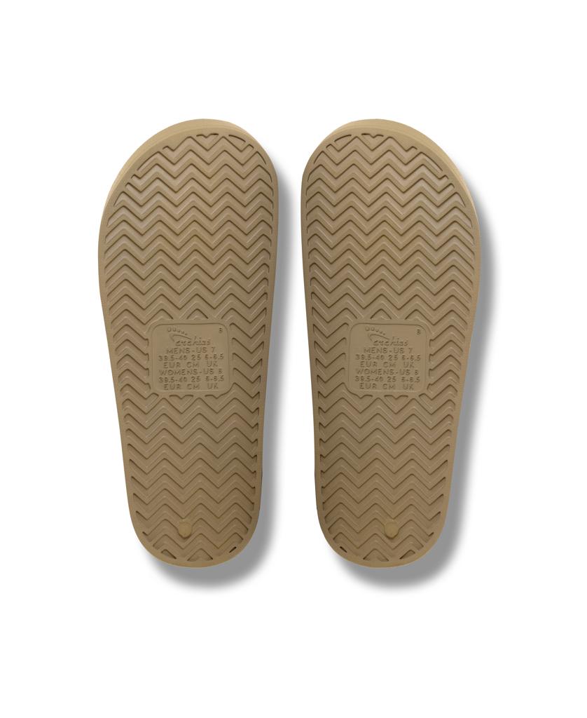 The Archies Archie Slide in Taupe features tan rubber soles with a herringbone tread, central branding, and built-in arch support for extra comfort.