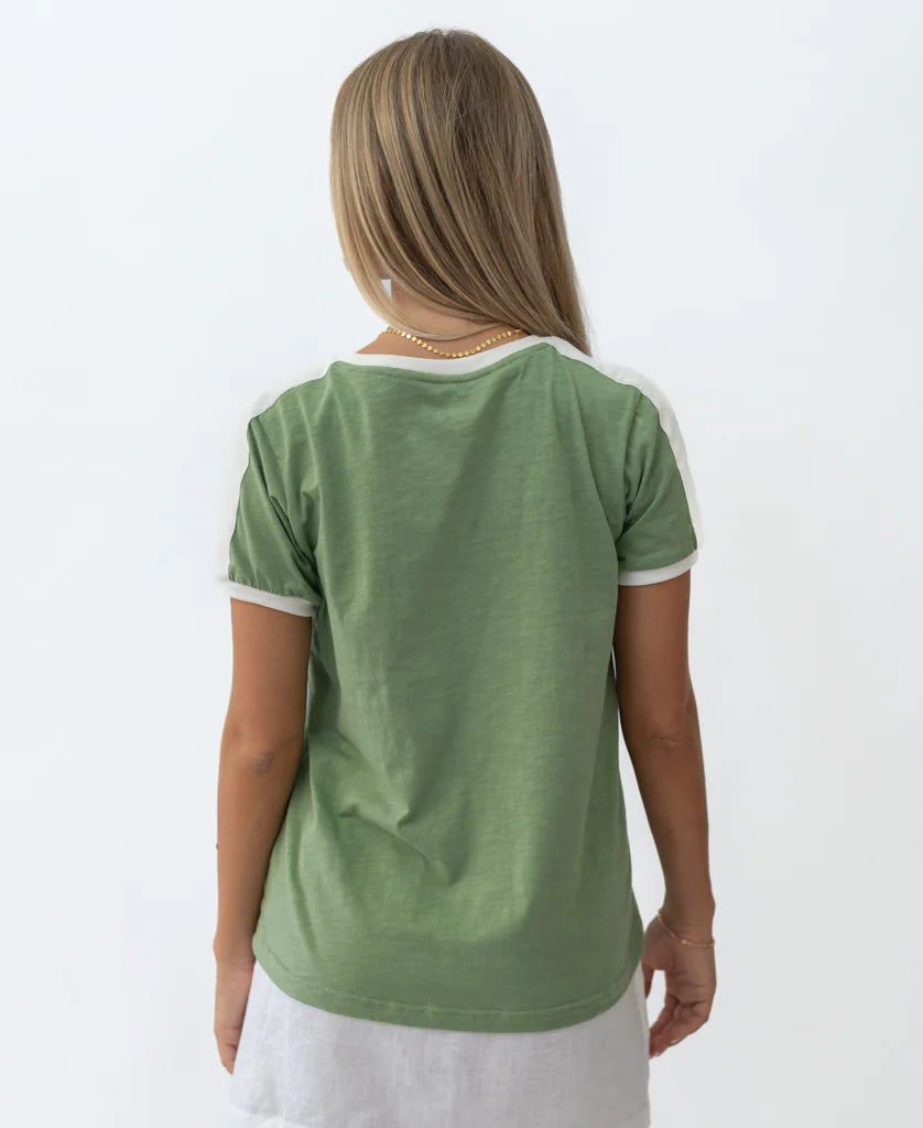 Woman seen from behind wearing a green Retro Ringer Tee | Moss with white trim on sleeves and collar, paired with a light-colored skirt against a plain white background.