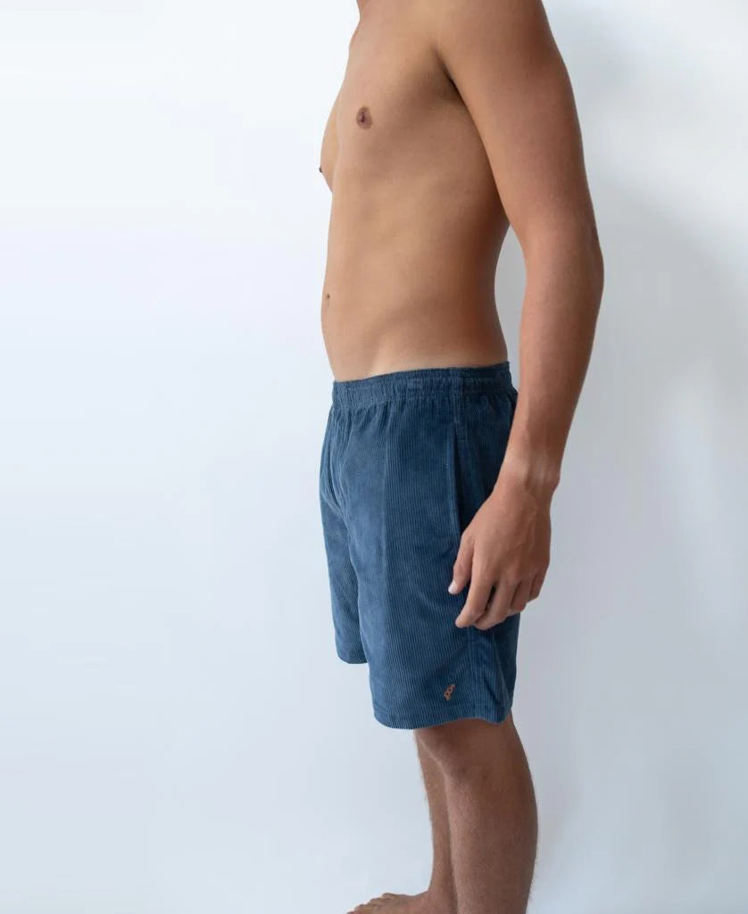 Side view of a man wearing Floyd Cord Elastic Waist Walkshort | Vintage Navy with elastic waistband against a plain white background.
