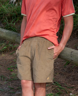 Person wearing Floyd Cord Elastic Waist Walkshort | Taupe standing outdoors near wooden fence, paired with coral short-sleeve shirt in casual natural setting.