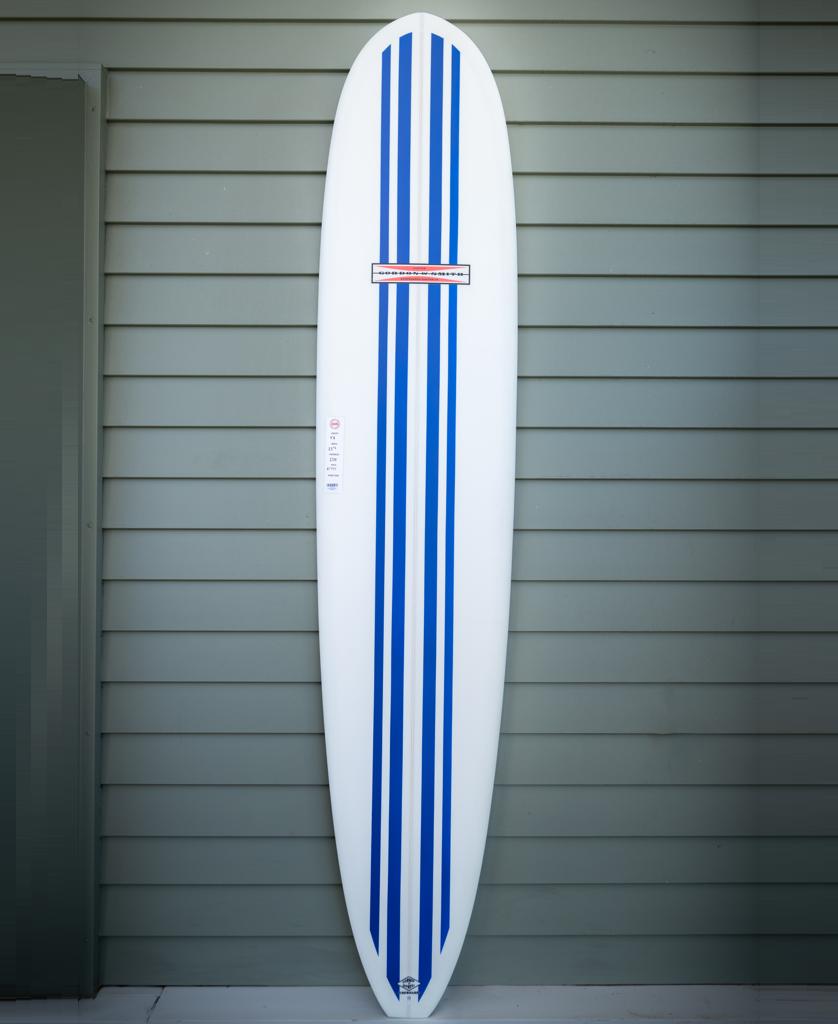 The Gordon & Smith G&S 94 Nosemaster Polish Finish in blue and white stands upright against a gray paneled wall.