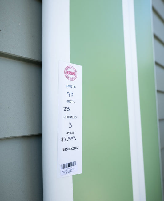 The Gordon & Smith G&S 93 Easy Rider (Polish Finish) in green/white, sized 9’3” x 23” x 3”, and priced at $1,999, leans against a wall.