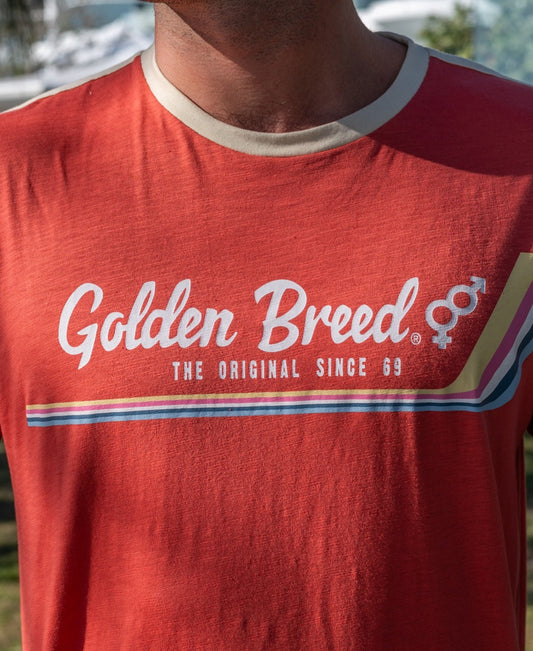 A person wearing the Golden Breed Retro Ringer Tee | Wash Red featuring THE ORIGINAL SINCE 69, retro stripes, male and female symbols, and classic 70’s style.