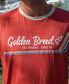 A person wearing the Golden Breed Retro Ringer Tee | Wash Red featuring THE ORIGINAL SINCE 69, retro stripes, male and female symbols, and classic 70’s style.