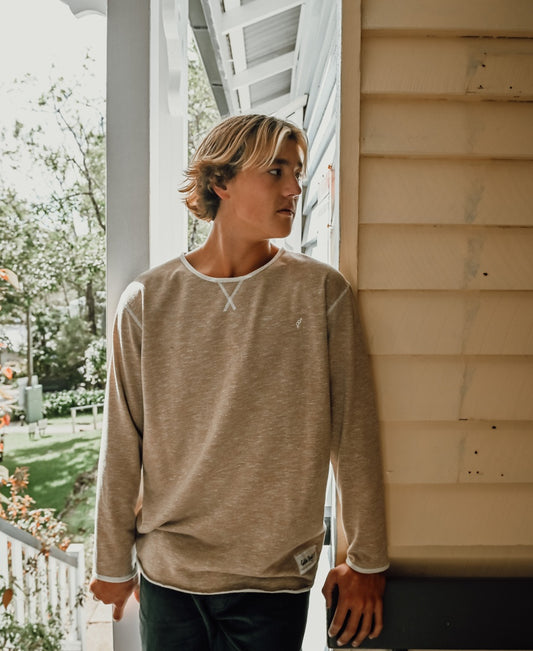 A young person with shoulder-length hair wears the Golden Breed Classic Rag Top in Coffee Marle, standing on a porch and looking to the side.