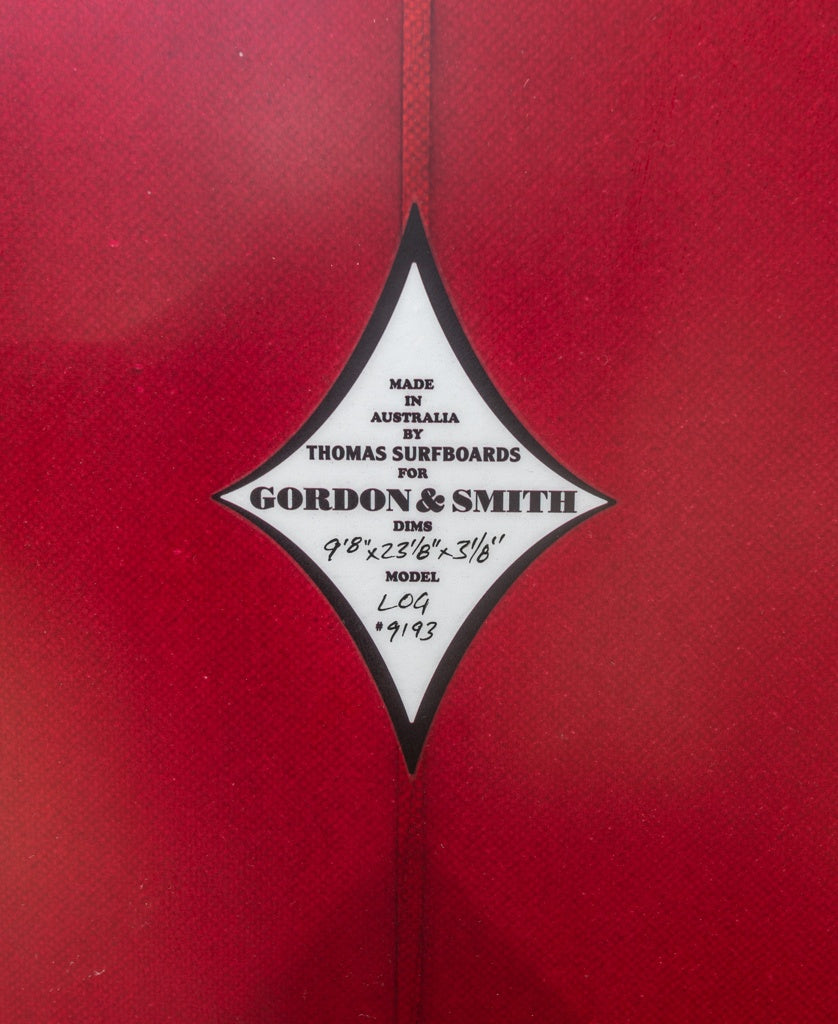 Close-up of a diamond-shaped label on a red G&S Log Cardinal 98 surfboard by Gordon & Smith.