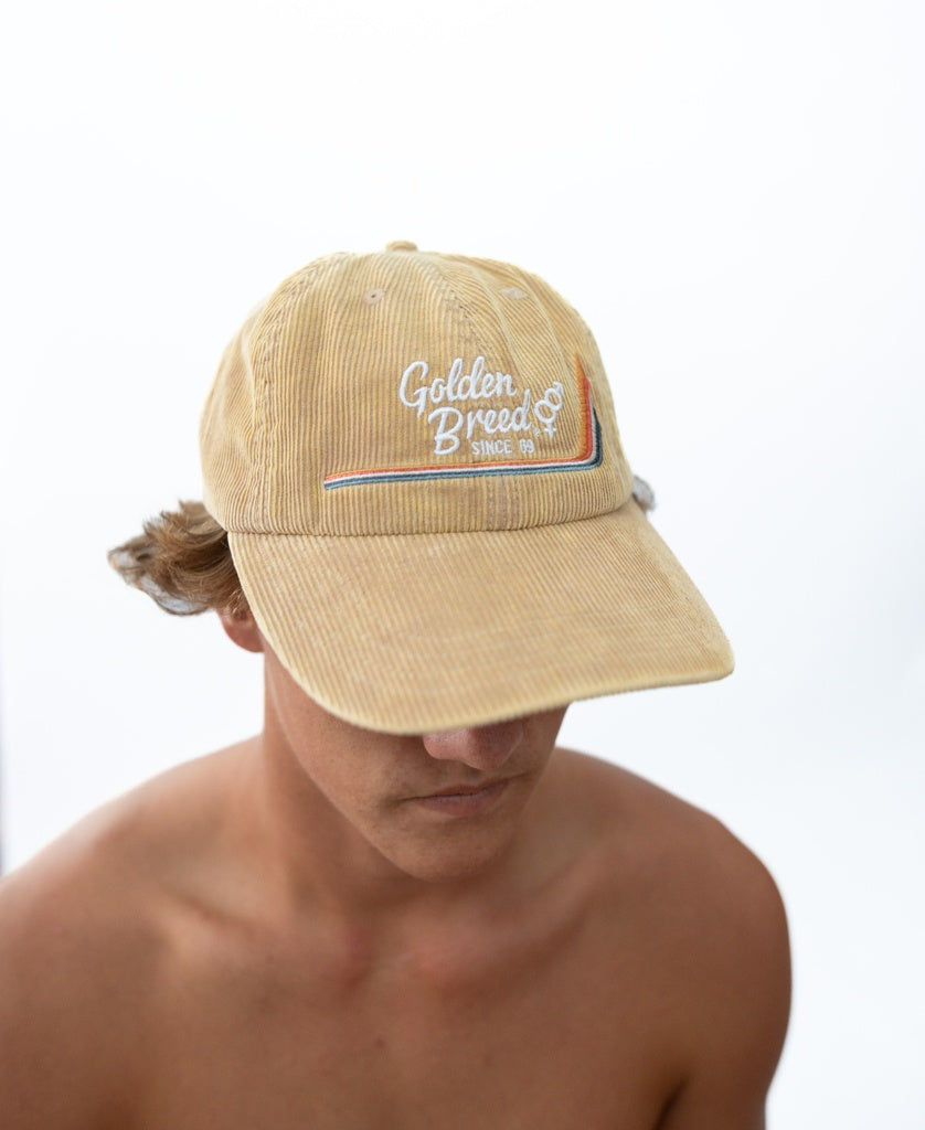 A shirtless person wears a Golden Breed Hancock Cord Cap in Camel with Since 69 embroidered on the front, set against a plain white background.