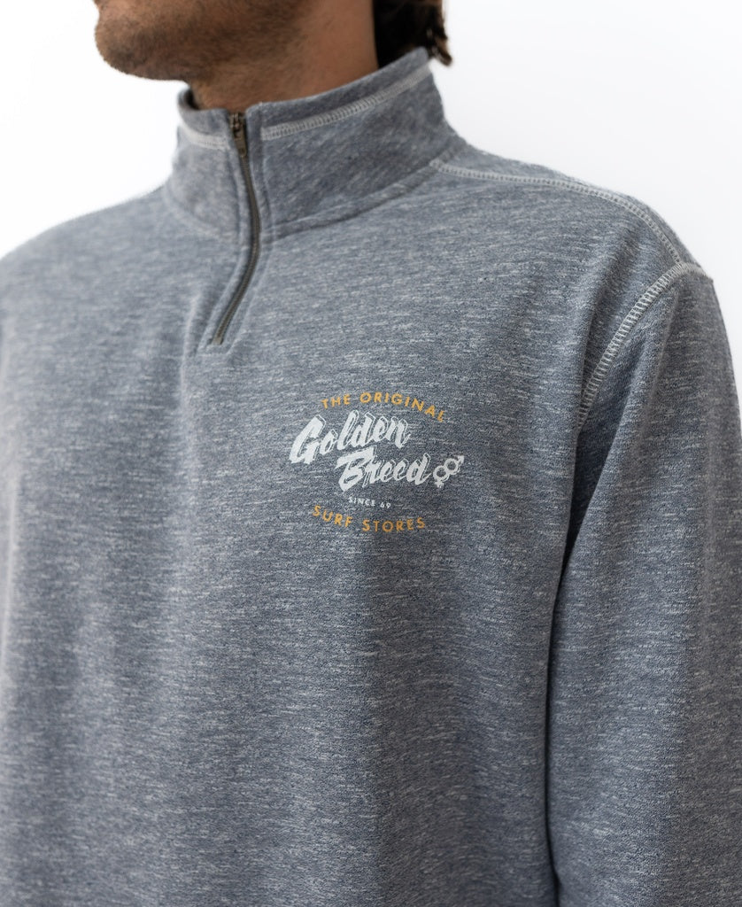 Someone wearing a navy marle Golden Breed Break 1/4 Zip Rag Top, made from soft French Terry, featuring Surf Stores and a small logo on the left chest.