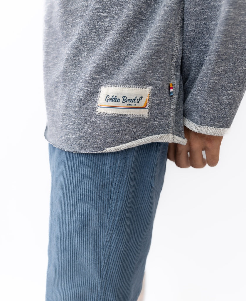 Person wearing a navy marle Break 1/4 Zip Rag Top by Golden Breed with blue corduroy pants, photographed from the side at waist height.