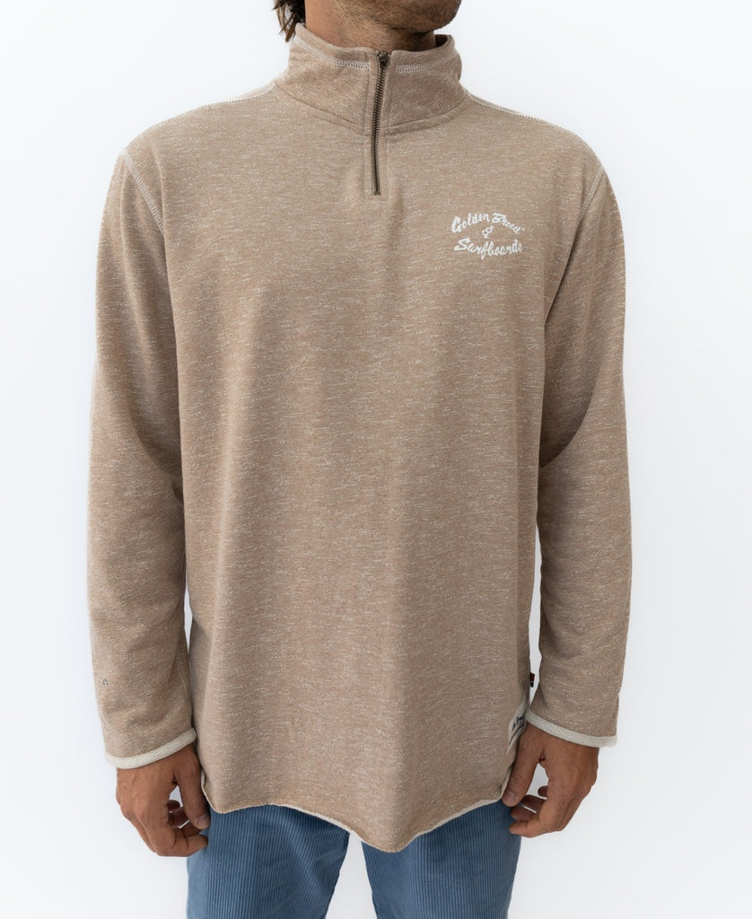 A person wears the Golden Breed Fin 1/4 Zip Rag Top in Mocha Marle, featuring Celtam Surfboards on the left chest, standing against a plain white background. This pullover blends comfort and style.