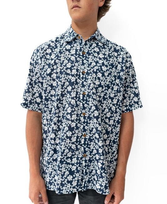 A person wearing the Golden Breed Liberty Floral Shirt in Vintage Navy, a short-sleeve button-up with a blue and white floral pattern, stands against a plain white background.