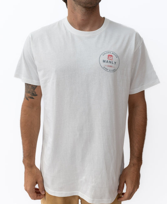 A man wears the Golden Breed Manly Kombi Tee in off white, featuring a classic fit and a small circular logo on the left chest that reads Golden Breed Manly 1969 Surf Store.