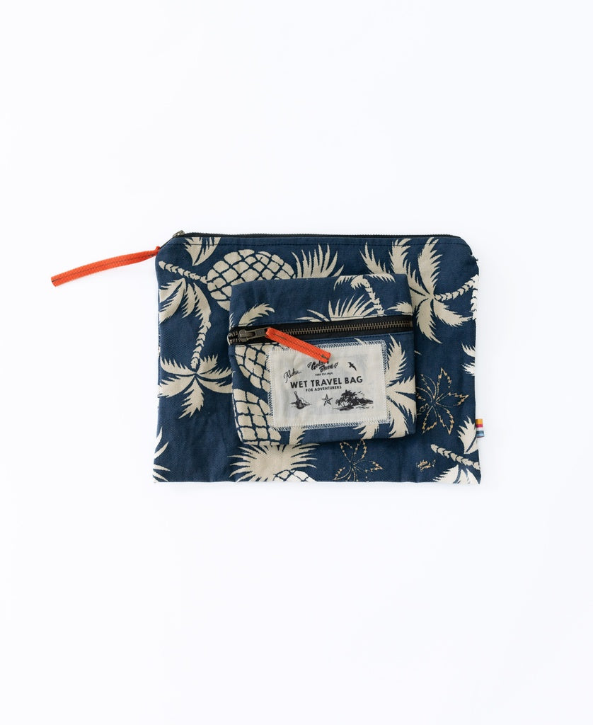 The Golden Breed Marco Wet Travel Bag | Navy, a water-resistant pouch with a beige tropical print, lies flat with a smaller clear wet bag placed on top.