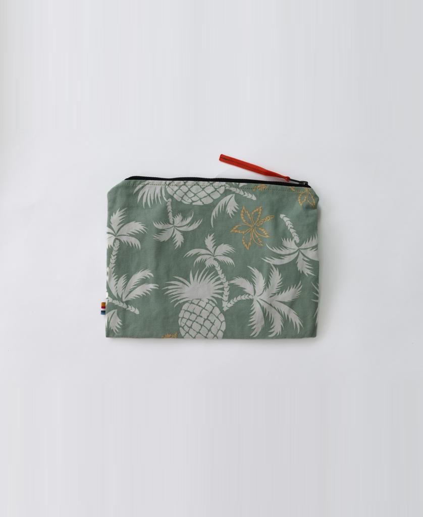 The Marco Wet Travel Bag | Sage by Golden Breed is a small, water-resistant pouch with a green background, white pineapples and leaves, a black zipper, and a red pull—ideal for carrying your essentials on the go.