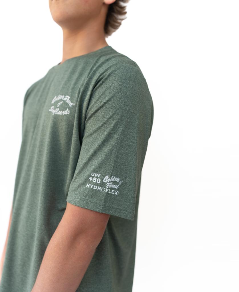 A person models the Golden Breed Nemo S/S Rash Shirt in Green Marle, featuring quick-drying fabric and white text on the chest and sleeve, against a plain white background.