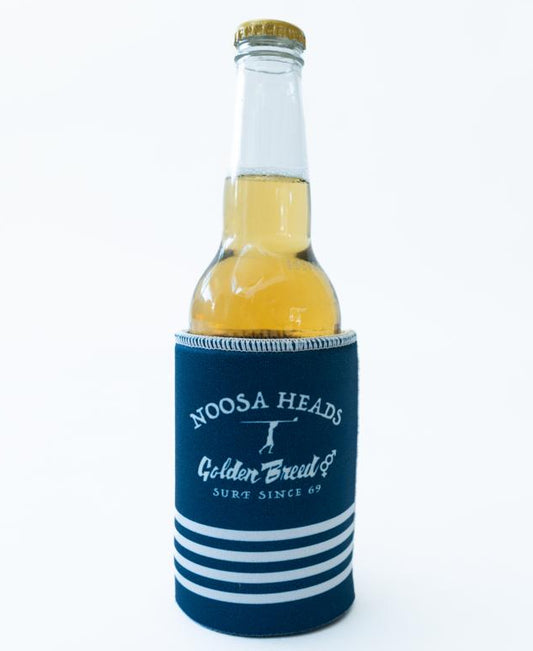 A bottle with a gold cap and yellow drink sits in a Noosa Stubby Beach Boy | Navy holder, branded Golden Breed.