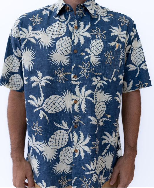 A person wearing the Golden Breed Pine-Palm Reverse Shirt in Vintage Navy, an oversized relaxed fit with short sleeves and a beige pine palm and pineapple print.