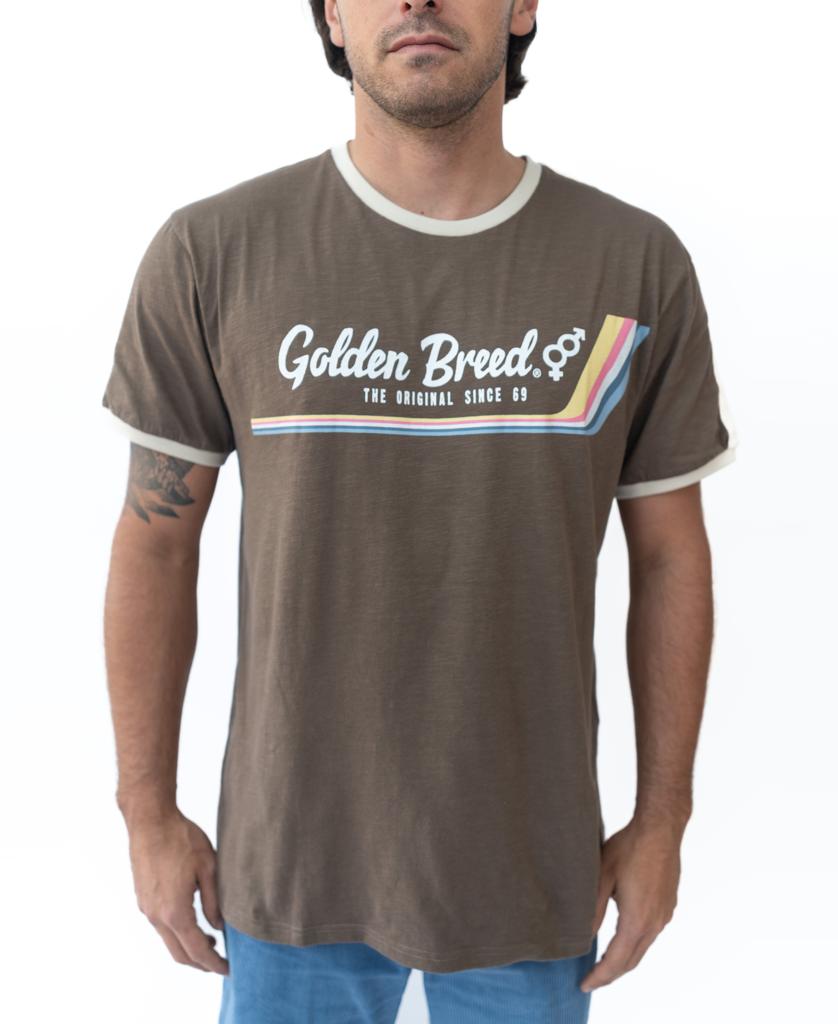 A man wears the Golden Breed Retro Ringer Tee in Wash Brown with white trim, The Original Since 69 text, and a multicolored chest stripe—channeling cool 70s style.
