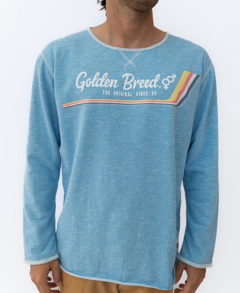 A man wears the Golden Breed Retro Rag Top | Sky Marle, featuring multicolored chest stripes and “The Original Since 69” slogan—effortlessly capturing a slouchy retro style.