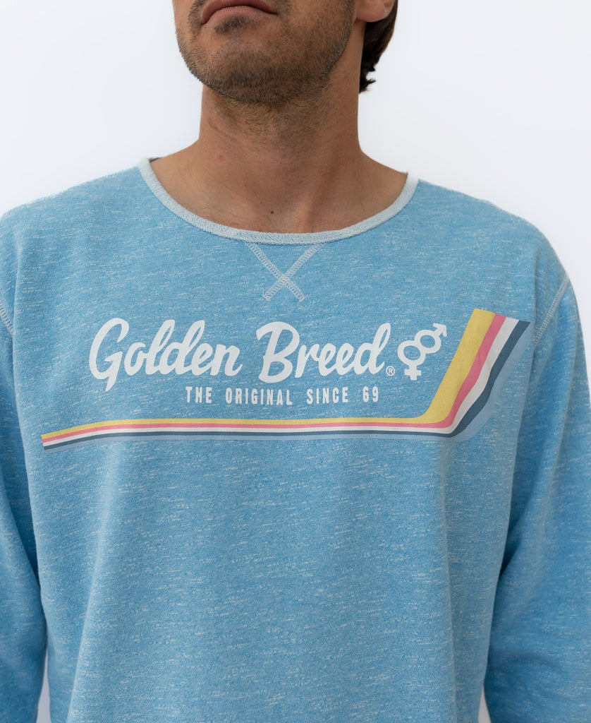 Someone wearing the Golden Breed Retro Rag Top in Sky Marle—a light blue, slouchy retro sweatshirt featuring The Original Since 69, an embroidered GB logo, and a colorful chest stripe.