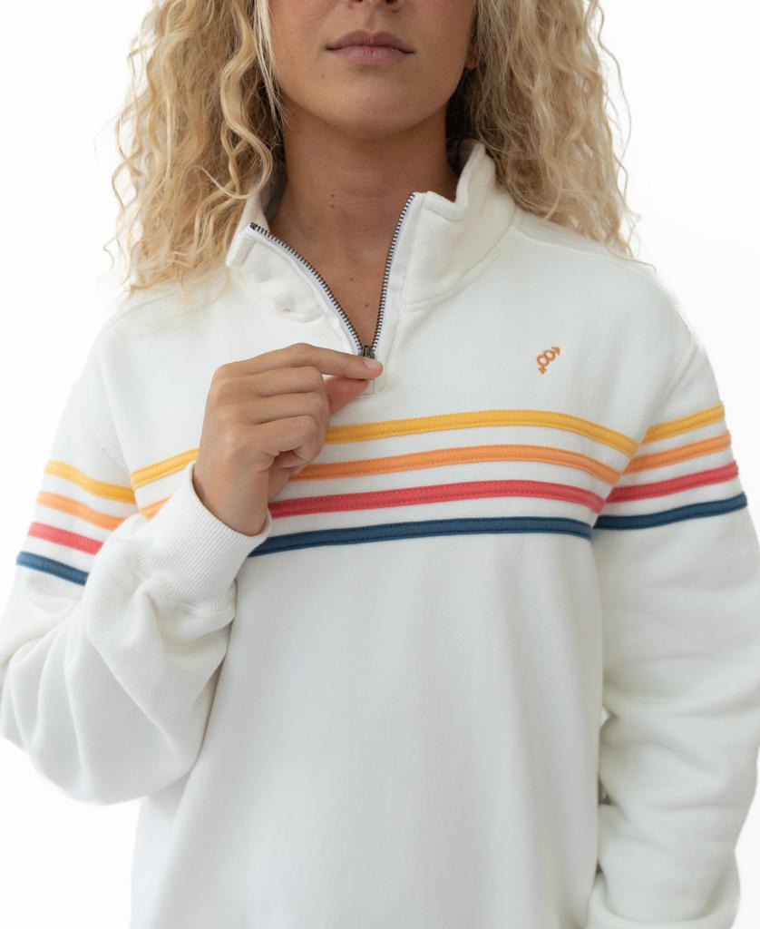A woman wears the Golden Breed Long Island 1/4 Zip in Off White, featuring orange, pink, and blue horizontal stripes, holding the zipper near her collar.