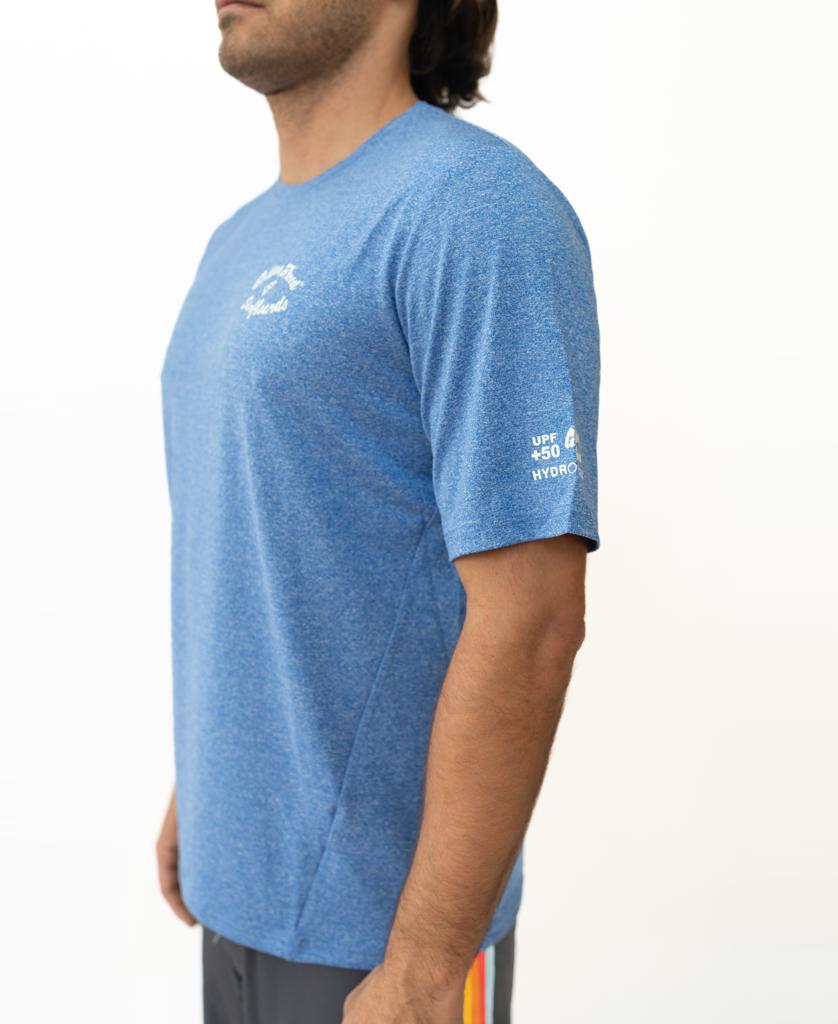 A man stands in profile wearing the Golden Breed Nemo S/S Rash Shirt in Blue Marle and dark shorts with yellow and red stripes, set against a plain white background.