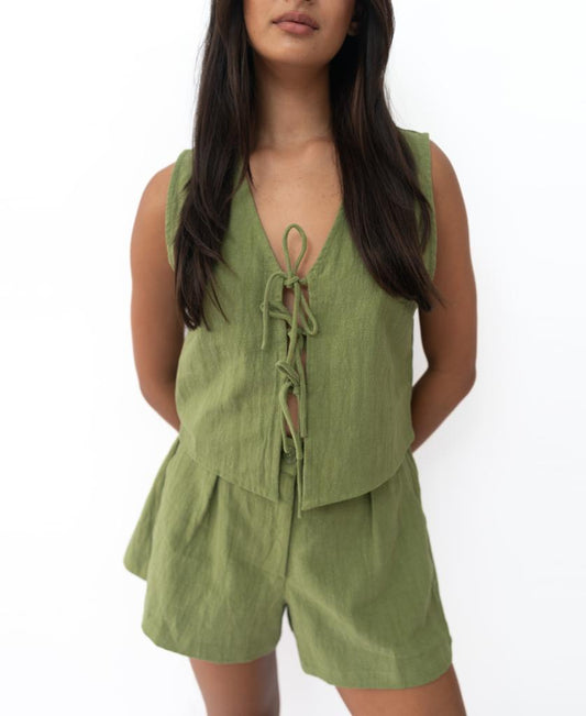 A woman wears the Lazy Beach Rennie Vest in Khaki—sleeveless with a lace-up front—paired with matching shorts, handmade in Bali, standing against a plain white background.