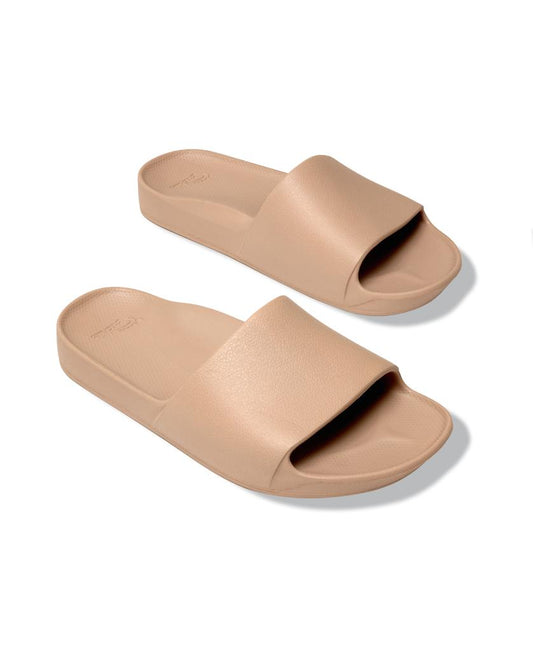 A pair of Archies Archie Slide sandals in Tan, featuring thick single straps and textured closed cell foam footbeds, displayed on a white background.
