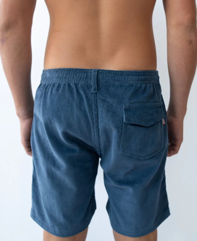 Rear view of a person wearing Floyd Cord Elastic Waist Walkshort | Vintage Navy made from textured corduroy fabric, featuring an elastic waistband and a single back pocket, ideal for casual surfwear style.