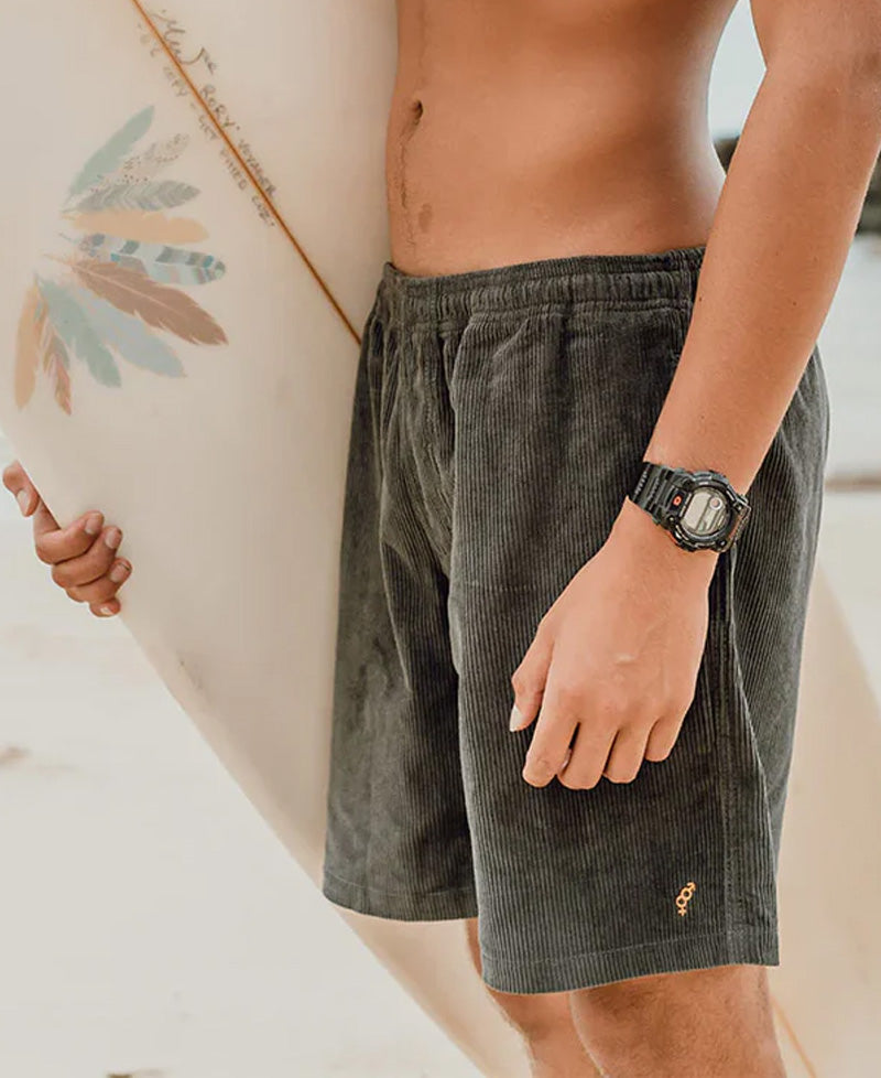 Close-up of a person wearing Floyd Cord Elastic Waist Walkshort | Wash Black holding a surfboard with feather artwork, showcasing casual surfwear style in an Australian beach setting.