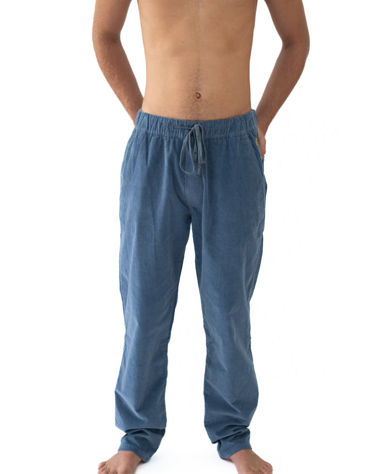 A man wearing Fred Stretch Cord Pant | Blue Mist, featuring a relaxed fit with an adjustable drawstring waist, showcasing comfortable casual wear from the Golden Breed surfwear shop in Australia.