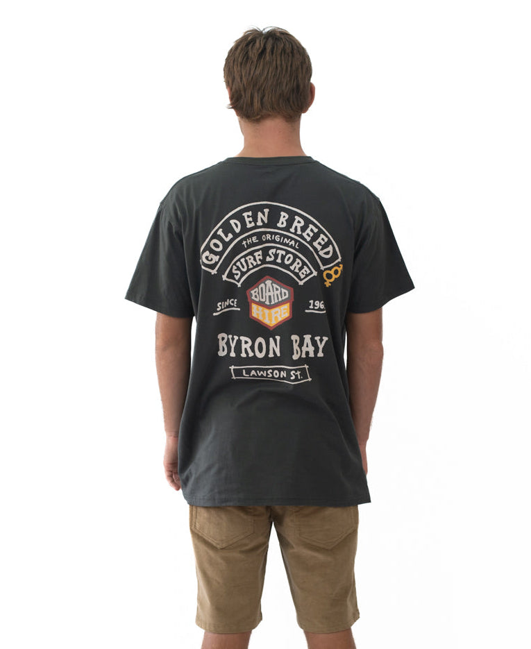 Man wearing a Byron Herring Tee | Wash Black with a surf-themed Golden Breed graphic on the back, styled with casual shorts, representing Australian surfwear culture.