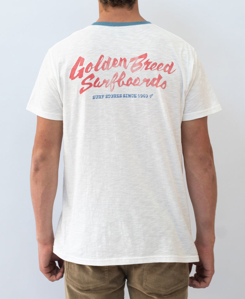 Back view of off-white Surf Loco Tee featuring red Golden Breed Surfboards script and blue trim on the collar.